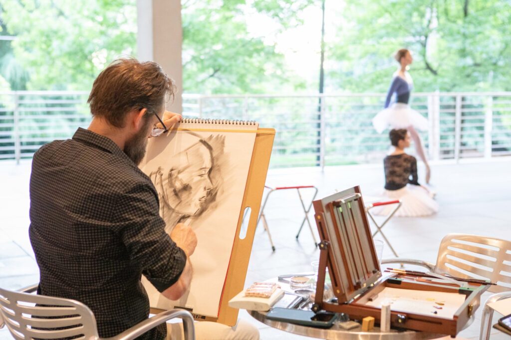 a man draws a ballerina wearing a tutu in the Orkin Terrace at the High Museum.