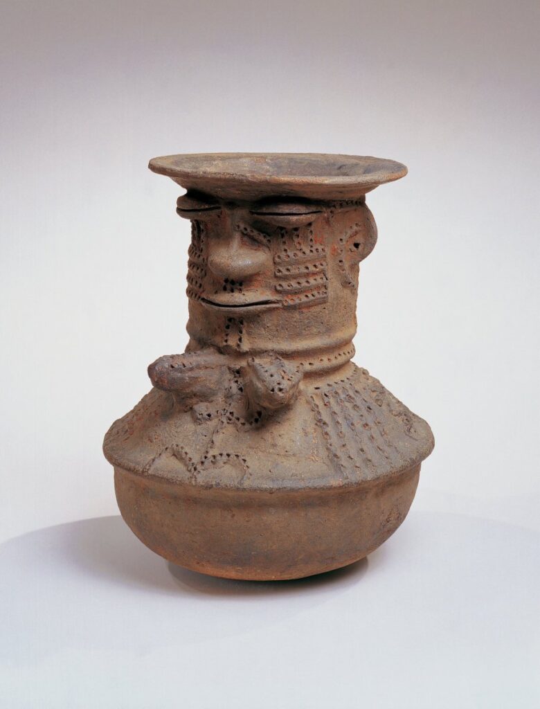 terracotta vase with a face and breast sculpted along its side.
