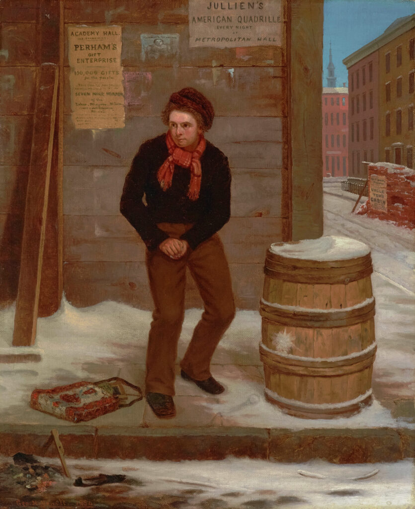 a boy with a serious expression in a red scarf and black sweater standing next to a snow covered barrel prepares a snowball.