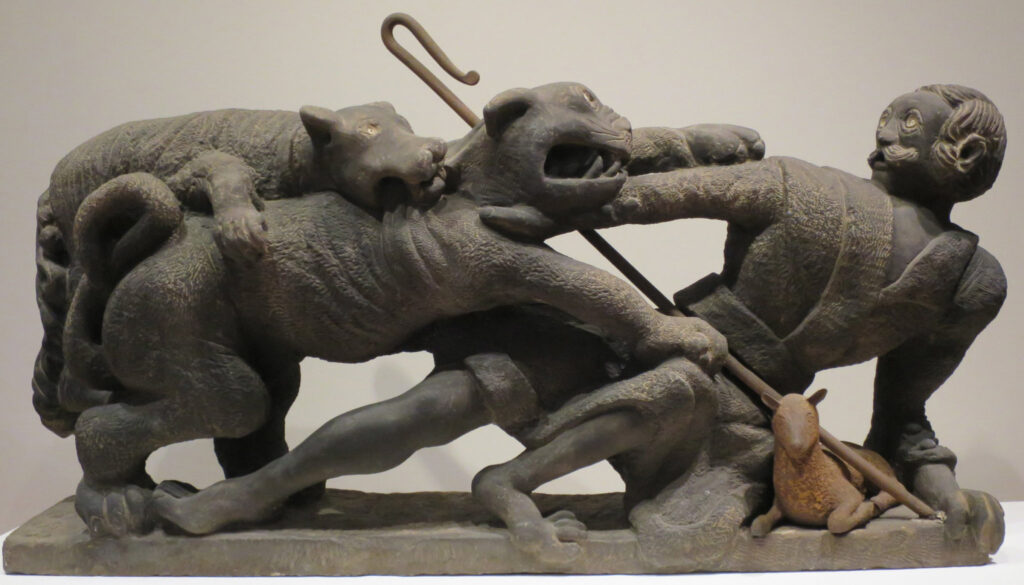 dynamic stone sculpture of a shepherd who protects his sheep and while being attacked by a mountain lion. The shepherd's dog defends his owner by lunging for the mountain lion.
