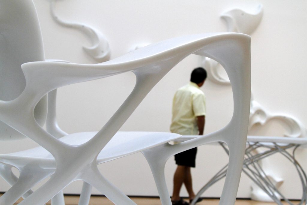 visitors walking through a gallery filled with organic white sculptures.