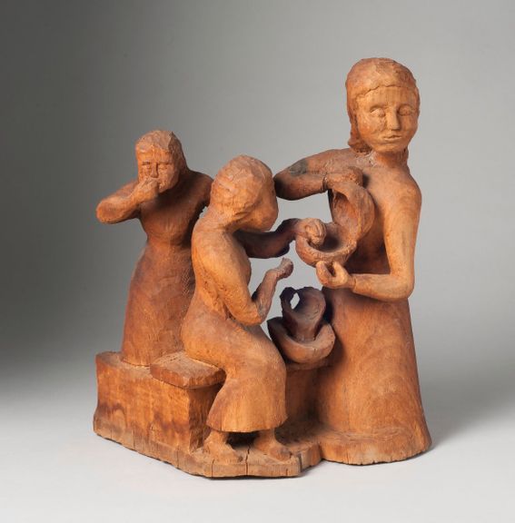 wooden sculpture of a mother with two children sharing a meal.