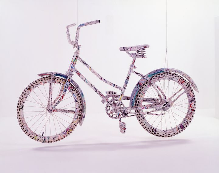 White bicycle encrusted and painted with celestial towers, tiny angels, names, and scriptures.